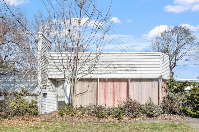 view of side of home with an outbuilding and a chimney