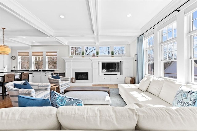 living room with beam ceiling, wood finished floors, a fireplace, and crown molding