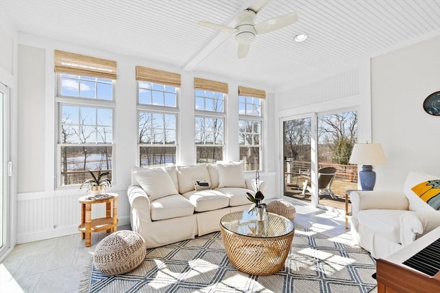 sunroom featuring beamed ceiling and a ceiling fan