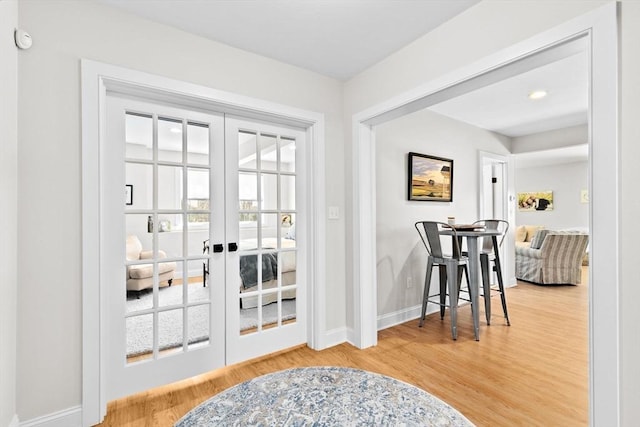 doorway with french doors, baseboards, and wood finished floors