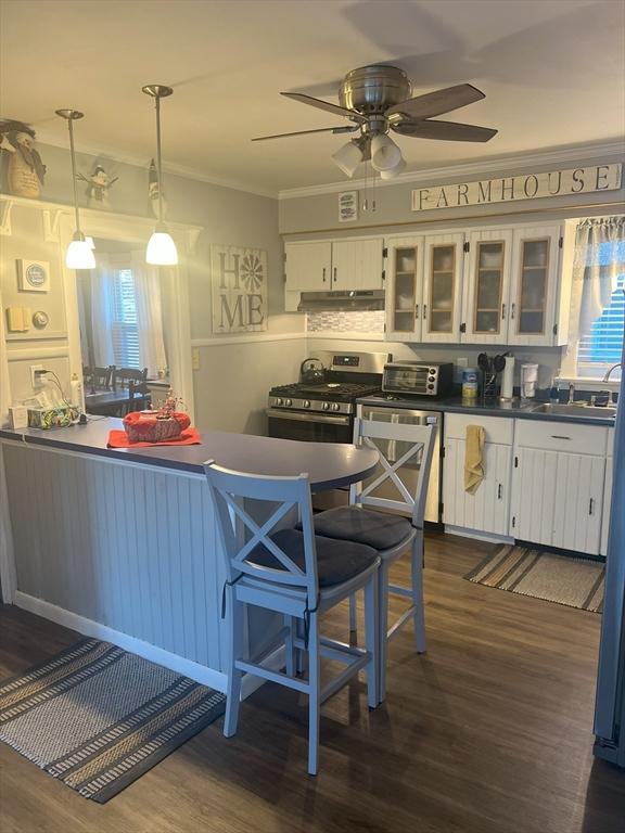 kitchen with dark countertops, white cabinetry, glass insert cabinets, and decorative light fixtures