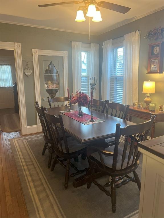 dining room featuring baseboards, crown molding, hardwood / wood-style floors, and ceiling fan