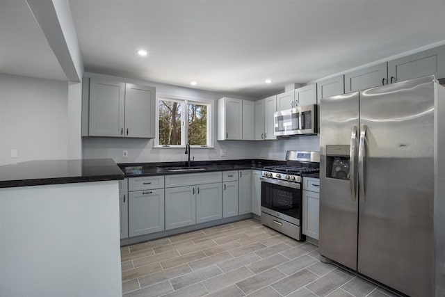 kitchen featuring wood finish floors, recessed lighting, a sink, appliances with stainless steel finishes, and dark countertops