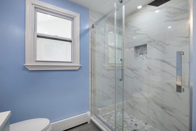 full bath featuring a marble finish shower, a baseboard heating unit, and toilet