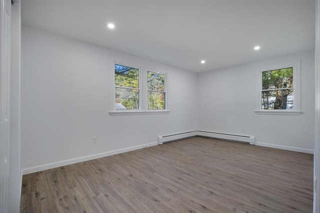 spare room with recessed lighting, a baseboard heating unit, baseboards, and wood finished floors