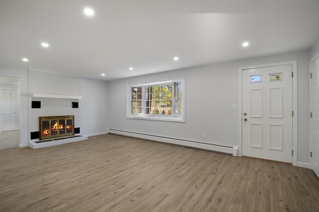 unfurnished living room featuring a baseboard heating unit, recessed lighting, wood finished floors, and a fireplace