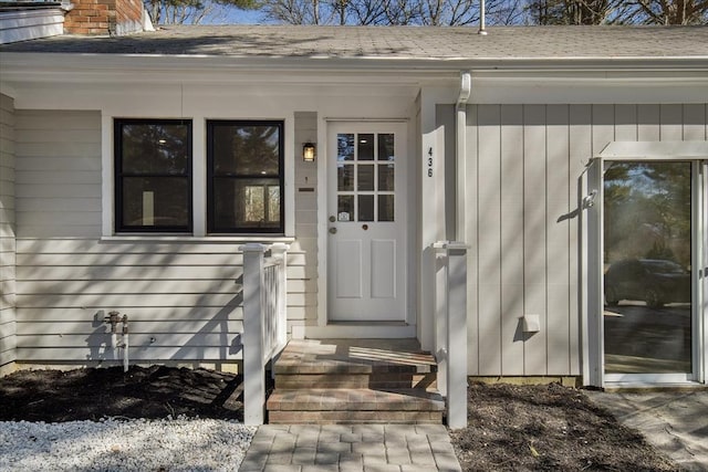 property entrance with a chimney and a shingled roof