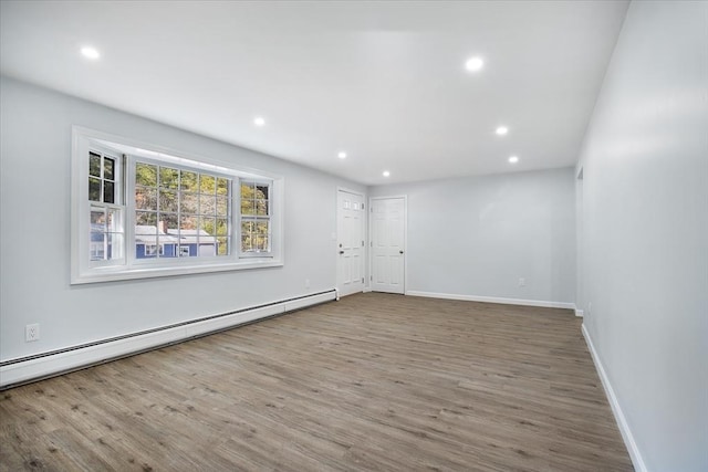 spare room with recessed lighting, a baseboard heating unit, baseboards, and wood finished floors