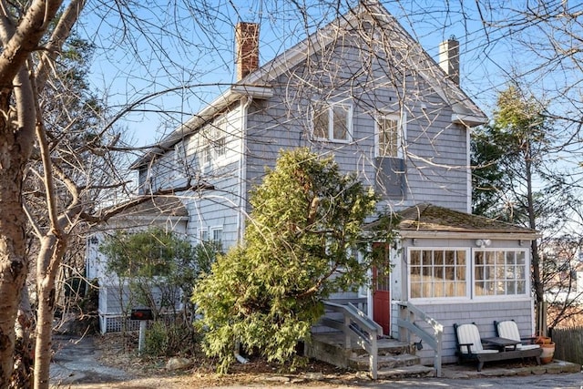 view of front facade with entry steps and a chimney