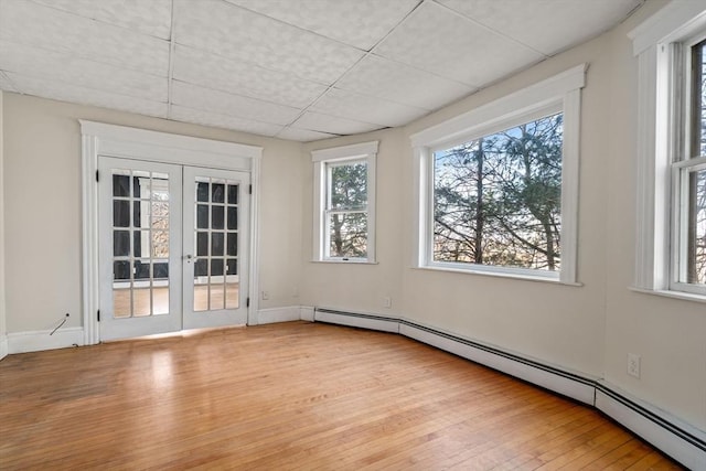 spare room with wood-type flooring, french doors, plenty of natural light, and baseboard heating