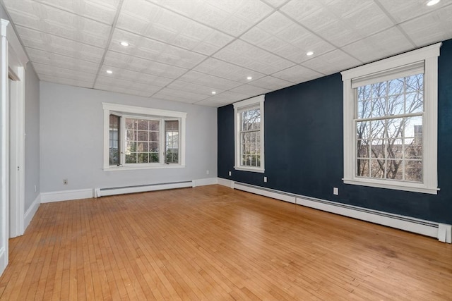 spare room featuring hardwood / wood-style floors, a baseboard radiator, a healthy amount of sunlight, and a baseboard heating unit