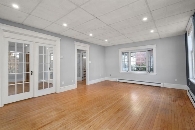 spare room with light wood-type flooring, a baseboard heating unit, baseboards, and french doors