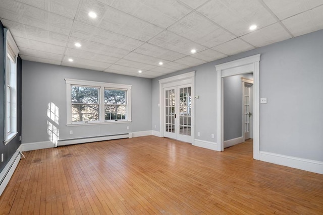 spare room with light wood-type flooring, a baseboard radiator, and baseboards