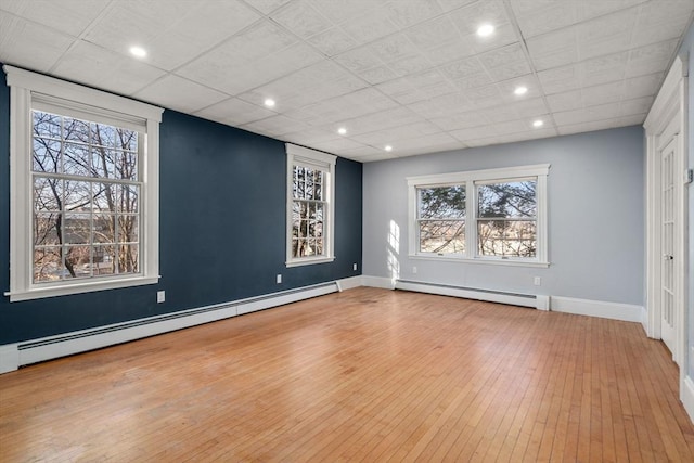 unfurnished room featuring recessed lighting, a baseboard heating unit, baseboards, and wood-type flooring