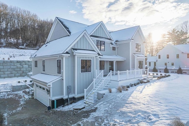 snow covered house featuring a garage and a porch