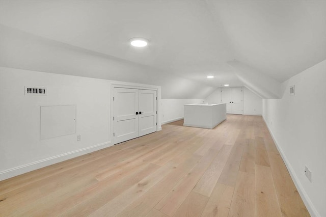 additional living space with light wood-type flooring and vaulted ceiling