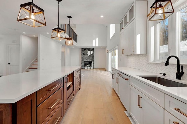 kitchen with sink, white cabinetry, backsplash, and hanging light fixtures