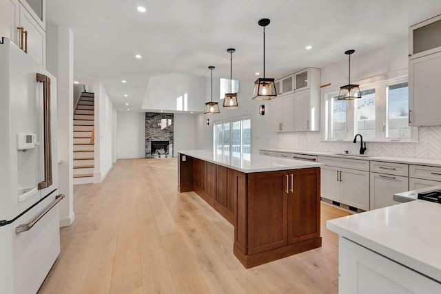 kitchen with high end fridge, a center island, decorative light fixtures, white cabinets, and sink