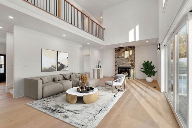 living room featuring a high ceiling, light hardwood / wood-style flooring, and a fireplace