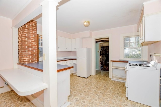 kitchen featuring white appliances, white cabinets, ornate columns, light floors, and crown molding