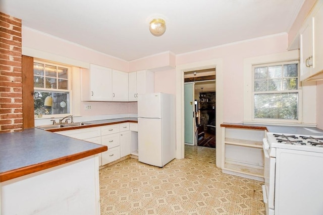 kitchen with white appliances, a sink, white cabinets, light floors, and crown molding