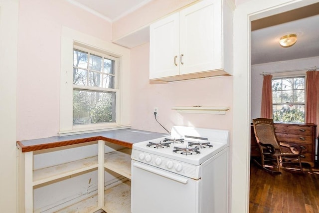 kitchen with dark wood-style floors, ornamental molding, white cabinets, and gas range gas stove