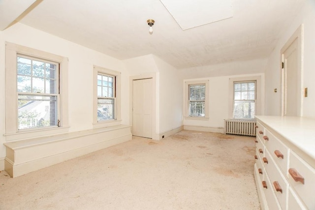 unfurnished room with baseboards, light colored carpet, and radiator