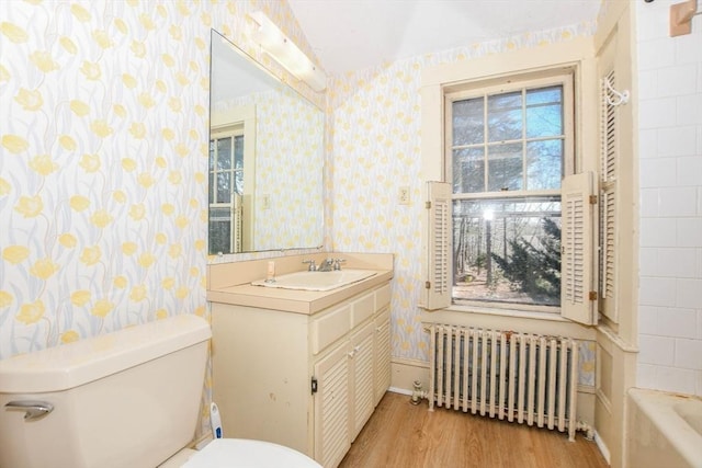 bathroom featuring wood finished floors, radiator, toilet, and wallpapered walls