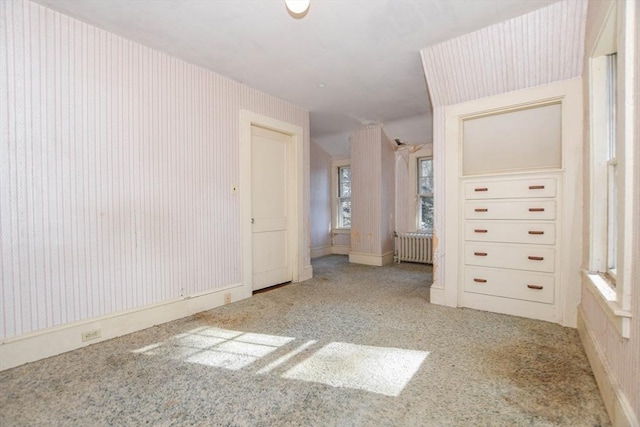 unfurnished bedroom featuring baseboards, wallpapered walls, carpet flooring, and radiator