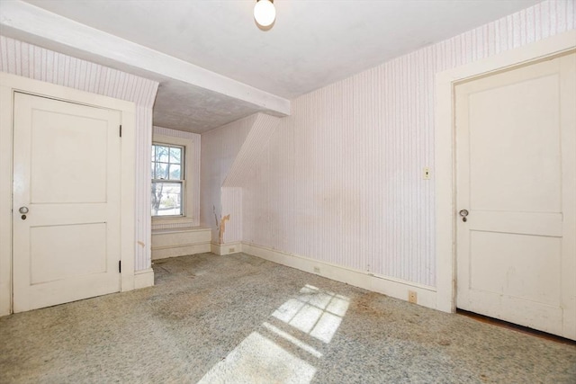 empty room featuring carpet floors, wallpapered walls, and baseboards