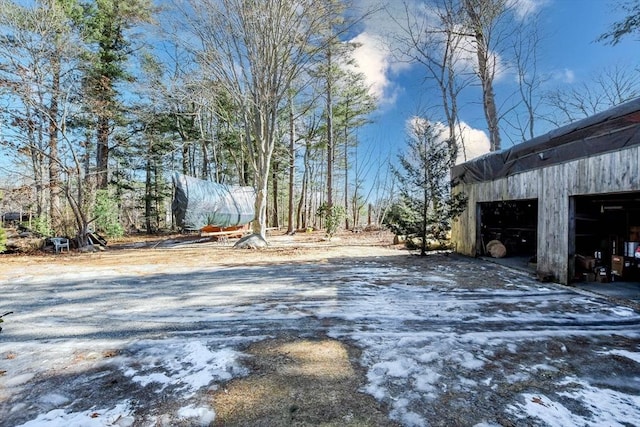 yard layered in snow featuring an outdoor structure and a detached garage