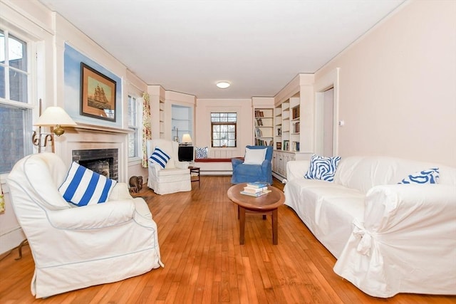 living area with light wood-type flooring, a brick fireplace, and baseboard heating