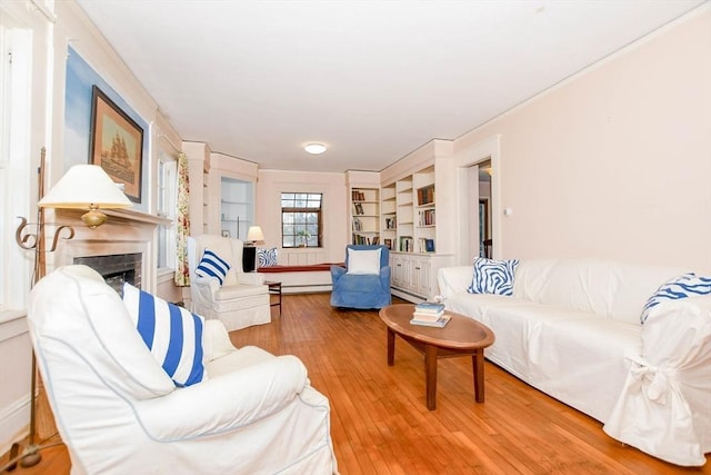 living room featuring a baseboard radiator, a fireplace, built in features, and wood finished floors