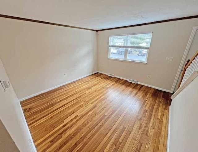 unfurnished room with light wood-style floors, visible vents, ornamental molding, and baseboards