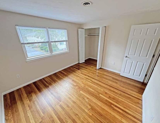 unfurnished bedroom featuring light wood finished floors, a closet, visible vents, and baseboards