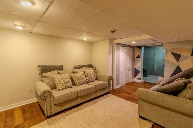 living room with a paneled ceiling and dark hardwood / wood-style floors