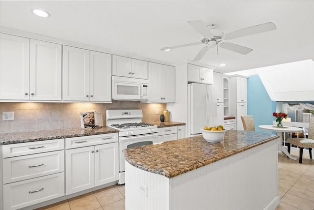 kitchen with decorative backsplash, a kitchen island, white appliances, and white cabinetry