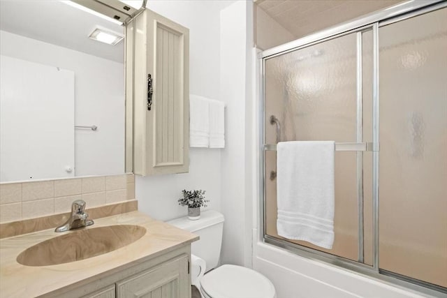 full bathroom with combined bath / shower with glass door, vanity, tasteful backsplash, and toilet