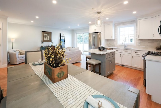 kitchen with a center island, decorative light fixtures, a kitchen bar, white cabinetry, and stainless steel appliances