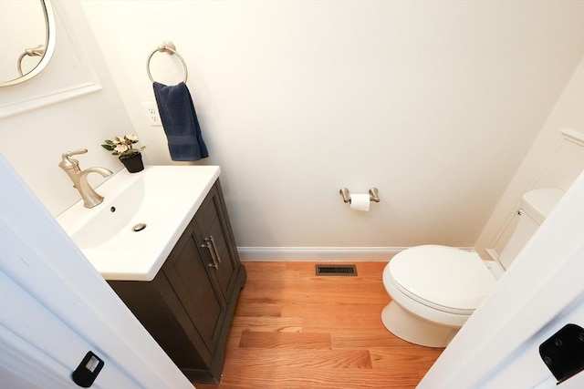 bathroom with wood-type flooring, vanity, and toilet