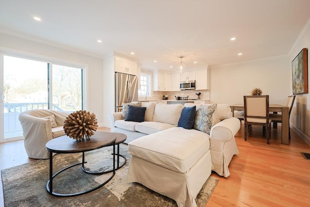 living room featuring crown molding, a wealth of natural light, and light hardwood / wood-style flooring