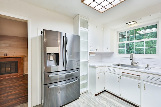 kitchen with decorative backsplash, white cabinets, light hardwood / wood-style flooring, stainless steel refrigerator with ice dispenser, and sink