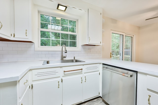 kitchen with stainless steel dishwasher, a wealth of natural light, sink, and white cabinets