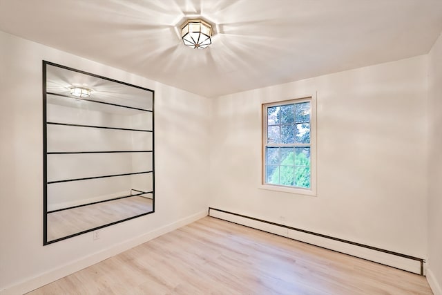 empty room with light hardwood / wood-style floors and baseboard heating