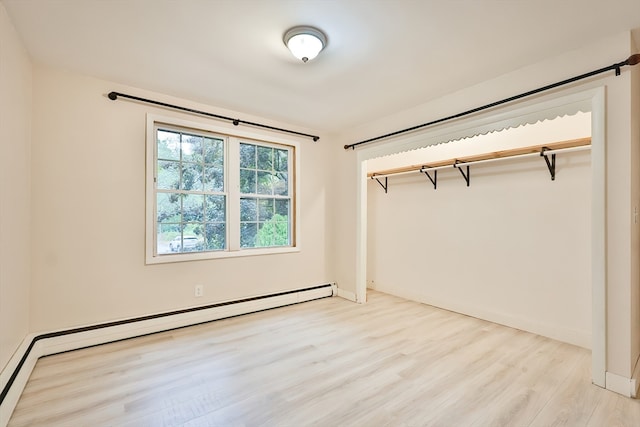 unfurnished bedroom featuring a baseboard heating unit, light hardwood / wood-style flooring, and a closet