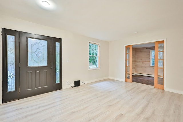 foyer with light hardwood / wood-style flooring, a baseboard heating unit, and wood walls