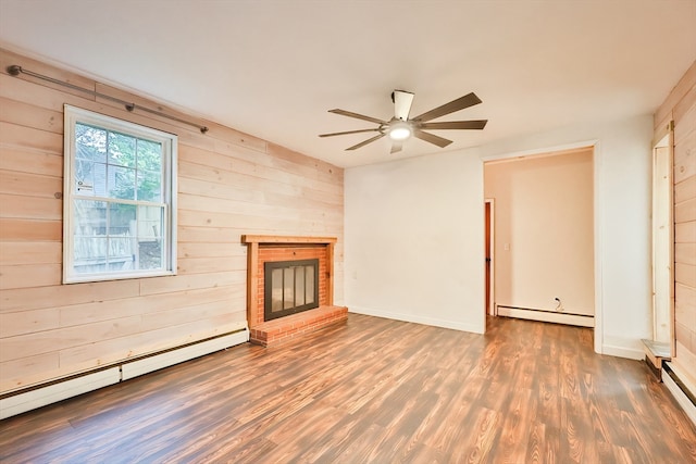 unfurnished living room with wood walls, ceiling fan, a baseboard heating unit, and dark hardwood / wood-style flooring