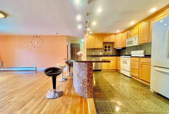 kitchen featuring a kitchen bar, backsplash, a baseboard radiator, white appliances, and light brown cabinetry