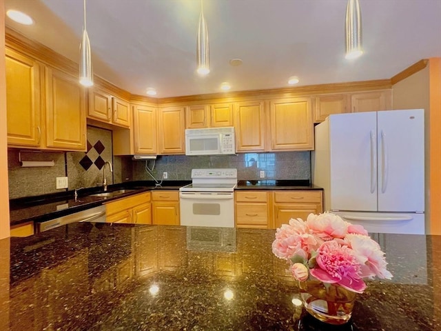 kitchen featuring decorative light fixtures, dark stone counters, sink, and white appliances