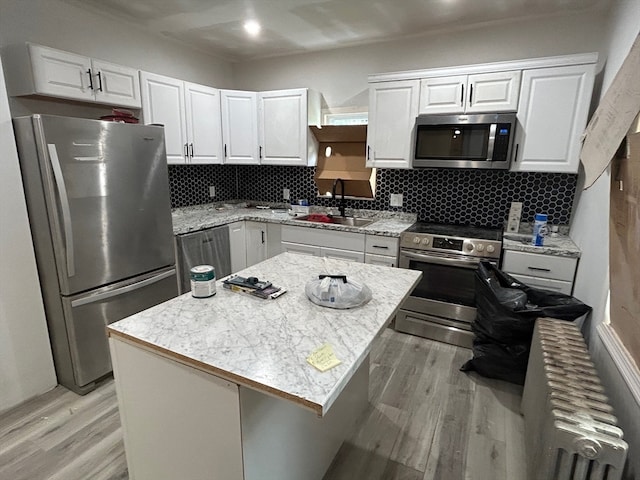 kitchen with a kitchen island, light hardwood / wood-style flooring, stainless steel appliances, and radiator